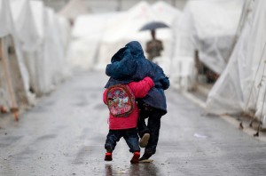 Syrian boys walk shoulder to shoulder in the rain at the Boynuyogun refugee camp on the Turkish-Syrian border in Hatay province